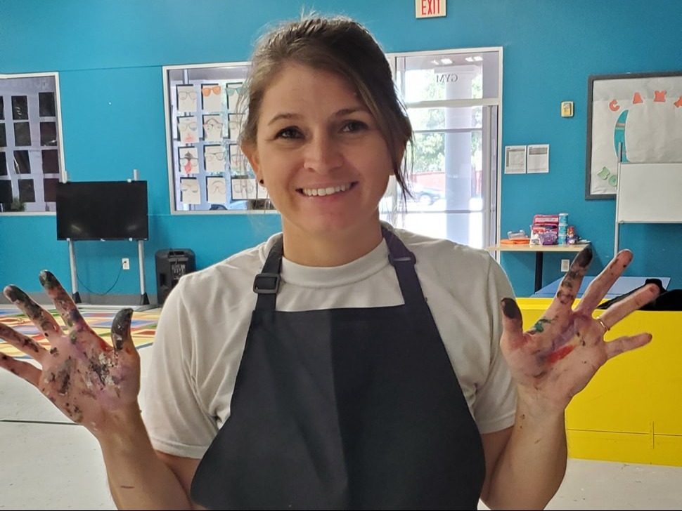Deleana smiling with painted hands raised for SIS Custom Creations